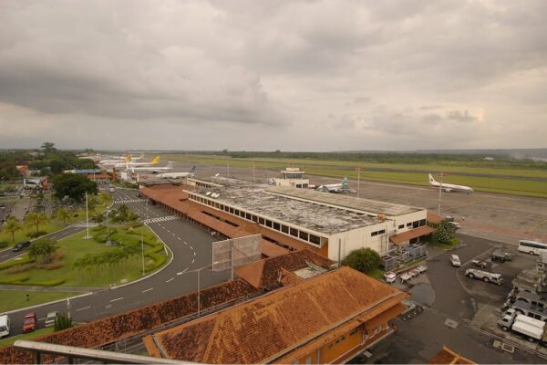 Vue aérienne du terminal et du tarmac de l'aéroport international Ngurah Rai (Denpasar, Bali), montrant plusieurs avions stationnés et la piste sous un ciel nuageux